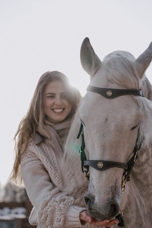Warm dressed woman with gray horse outside