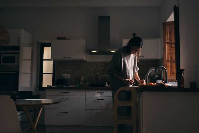 Woman cutting fruits while cooking in kitchen