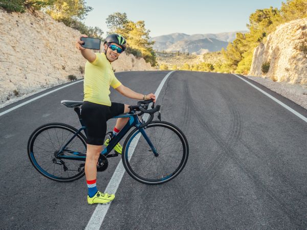 healthy man taking selfie after cycling in a mountain road in a sunny day