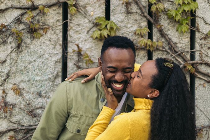 cute Black couple kissing on the cheek and smiling