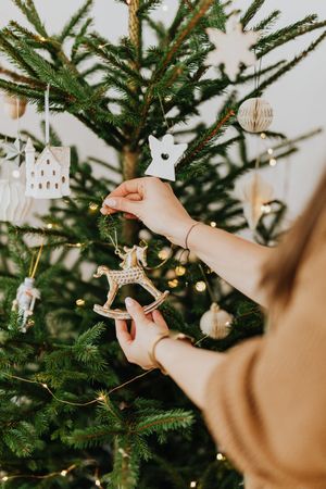 Cropped image of woman putting an ornament on Christmas tree