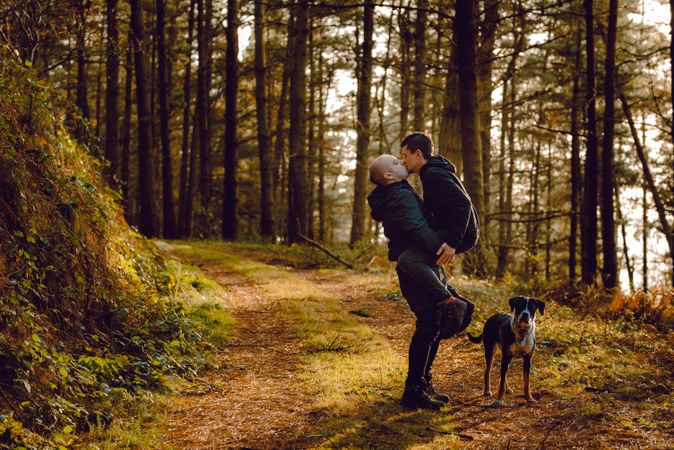 Men hugging and kissing on countryside road near dog