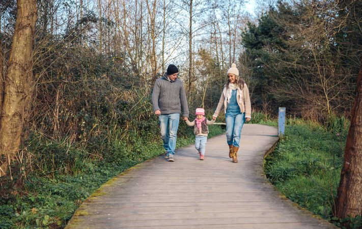 Parents walking with their young daughter on trail in forest