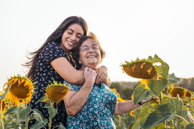 Taking advantage of life Grandmother and granddaughter in a field of sunflowers.