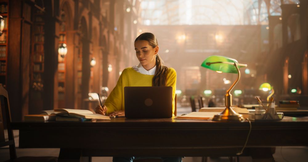 Dedicated Female Student Engaged in E-Learning at a Classic Library Desk.