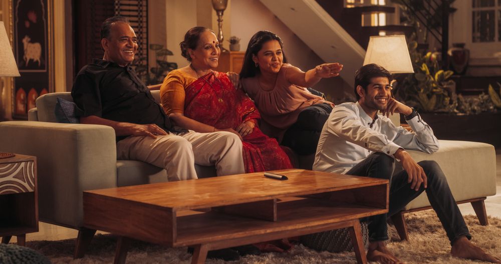 Portrait of Happy Indian Family Enjoying Movie Playing on TV at Home Together.