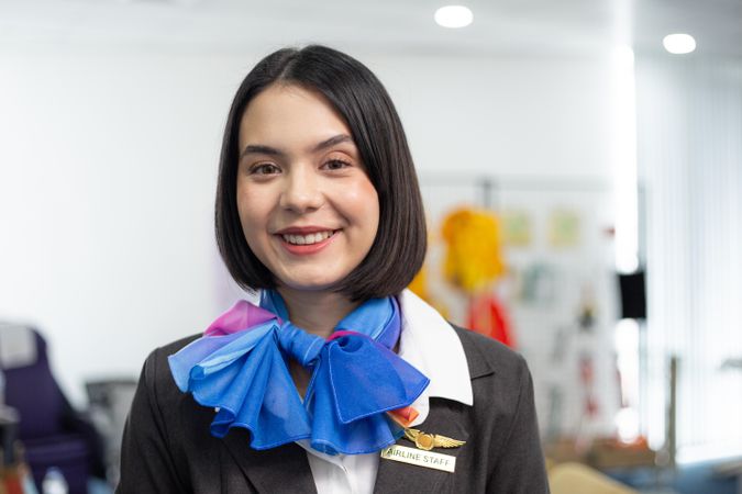 Smiling woman in silk scarf flight attendant uniform standing in airport