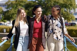 Three women walking over pedestrian bridge on summer’s day