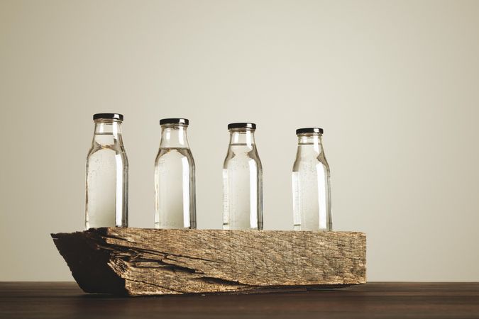 Four clear bottles in a row on wooden table