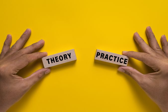 male hand hold wooden blocks with theory and practice words isolated on yellow background
