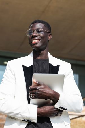 Content Black businessman in stylish apparel with tablet outdoors