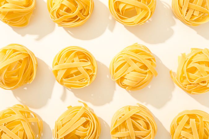 Flat lay composition with different pasta on light background, space for text and closeup