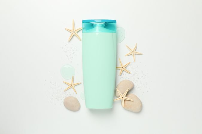 Blank cosmetic bottle and starfishes on light background