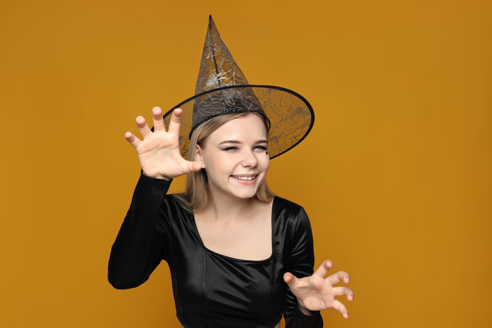 A woman in a witch's hat, with the gesture of scratching like a cat