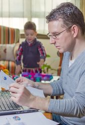 Father working in home office and son playing