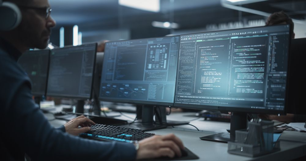 Close Up of a Software Developer Working on a Desktop Computer, Implementing New Features and Updates to a Company Server.