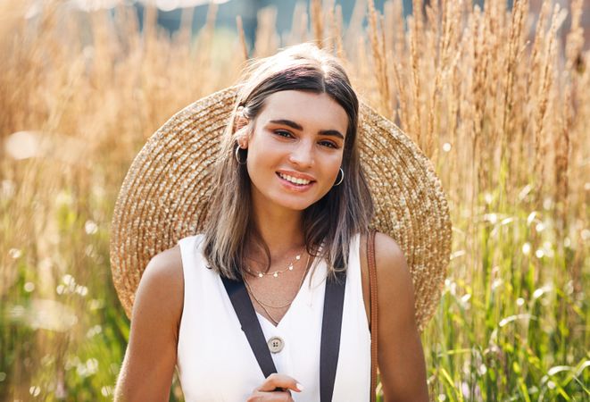 Portrait of happy woman with straw hat on her back in a field