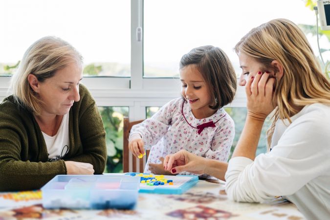 Woman playing board game with daughter and granddaughter