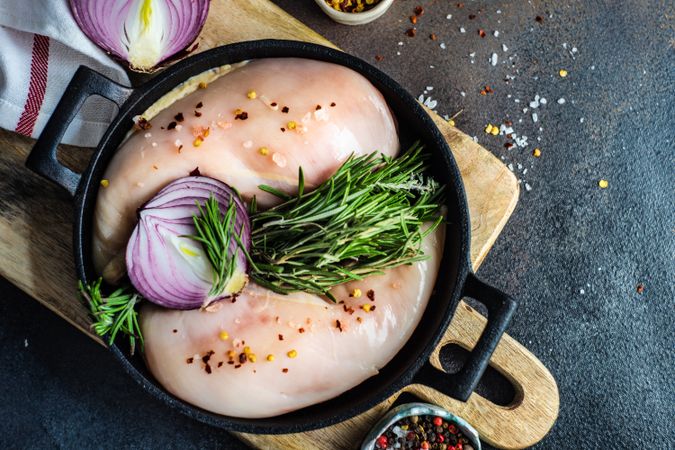 Top view of raw chicken in pan ready to cook on cutting board with space for text