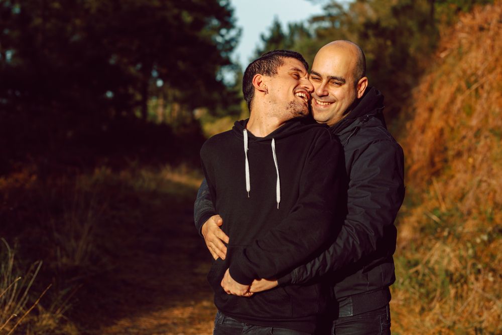 Smiling men hugging on path in park