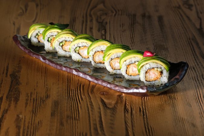 Delicious sushi rolls on marble plate on wooden table