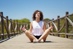 Calm woman sitting in lotus pose on pier