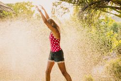 Cheerful teenager having fun with jet of water