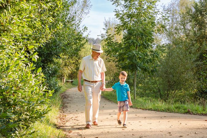 Grandfather and grandchild walking on path outdoors