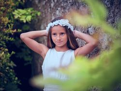 Pretty girl in white wreath touching head while standing near ol