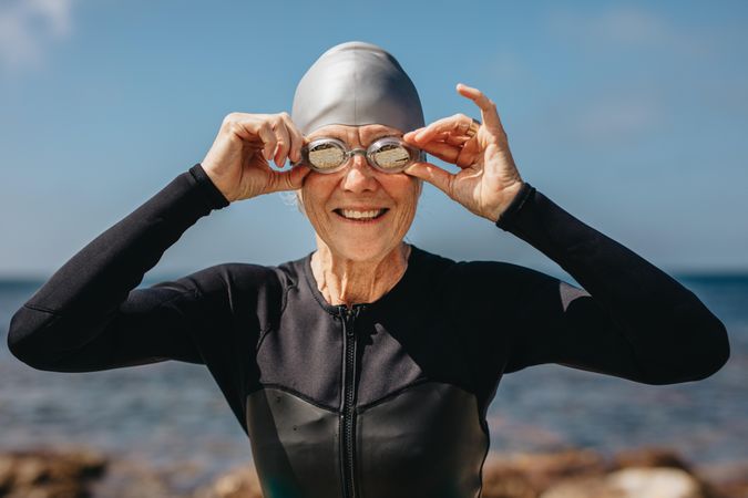 Portrait of a smiling older female swimmer with sea in the background