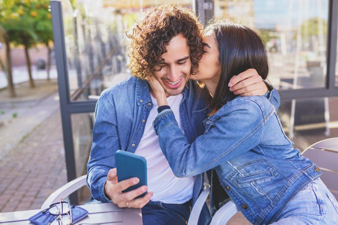 Male and female embracing while taking selfie sitting down outside