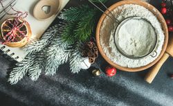 Top view of flour with sieve for Christmas baking on dark counter
