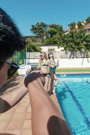 Friends playing with water pistols in the pool