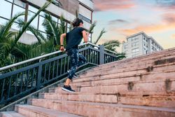 Female training running up stairs with dusk clouds