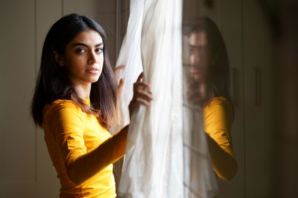 Woman opening curtains and gazing out the window