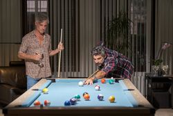 Mature men playing pool in game room