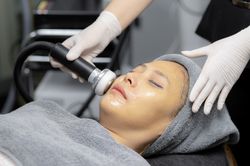 Young woman doing facial massage in beauty clinic.