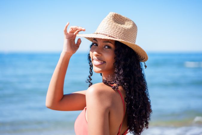 A Smiling Woman Wearing a Straw Hat, Enjoying a Beautiful Day at the Beach with Joy