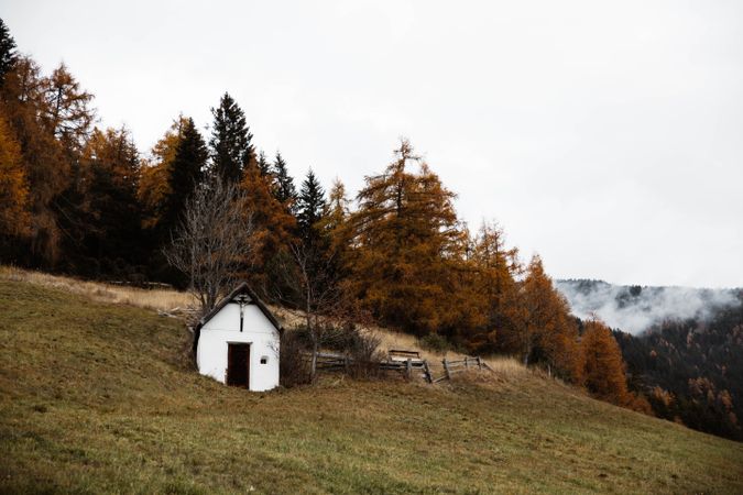 Small church on cliff near forest and mountains