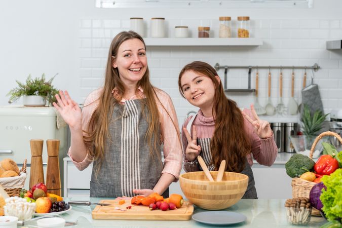 POV mother and daughter greeting to audience showing cooking homemade salad