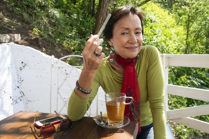 Woman posing with marijuana pipe and tea outside