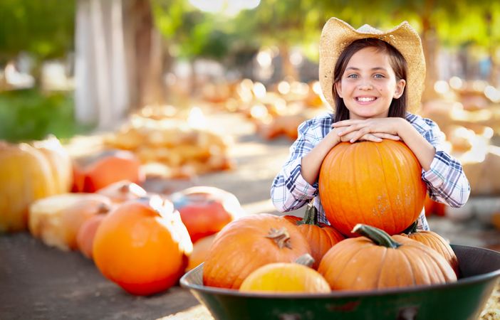 Girl Wearing Cowboy Hat Enjoying The Pumpkin Patch on a Sunny Fall Day.