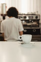 Cup of coffee on counter with barista in background