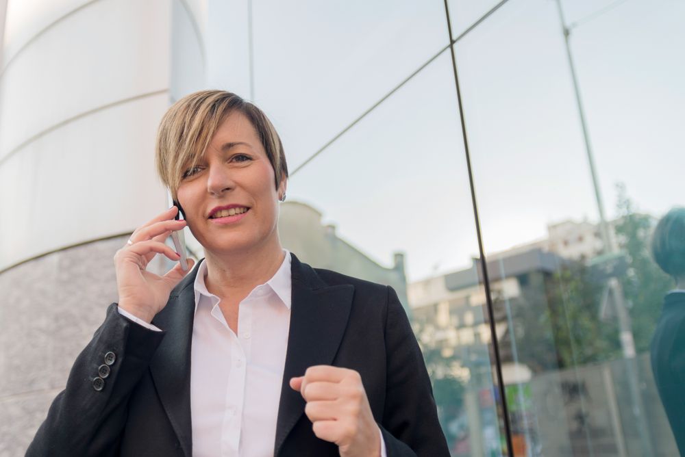 Businesswoman in blazer speaking on cellphone outside
