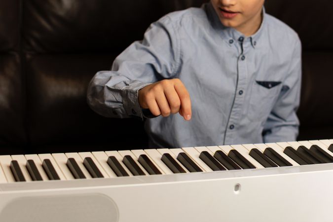 Boy pointing at key on the keyboard while playing.