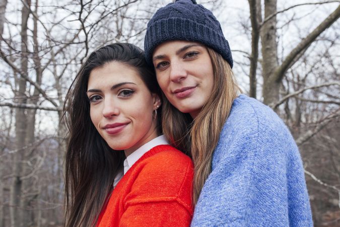 Smiling women in sweaters hugging in park