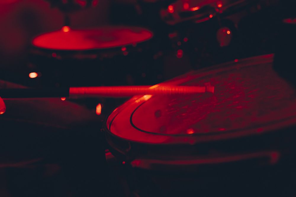 Man with drumsticks playing on drums in redness