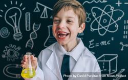 Happy kid laughing and showing yellow liquid in flask 5RVKRO