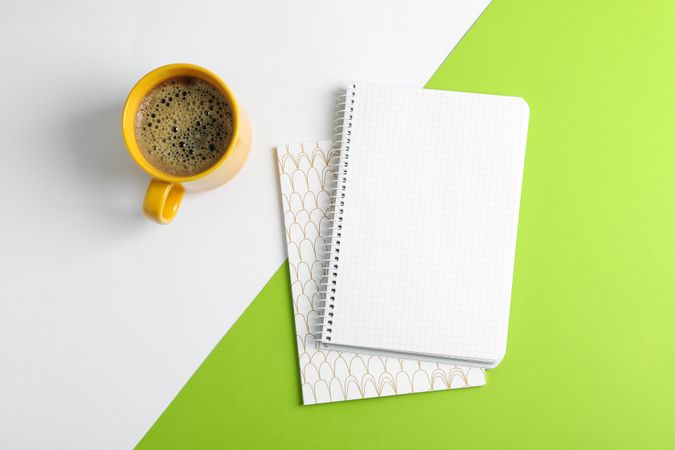 Cup of coffee with copybooks on color background, top view