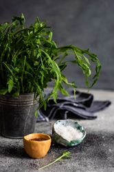 Two small bowls of flax seeds and salt with fresh arugula 